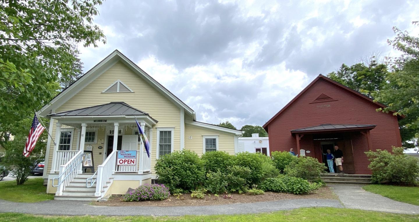 Two quaint buildings, one yellow and one red, under a cloudy sky.
