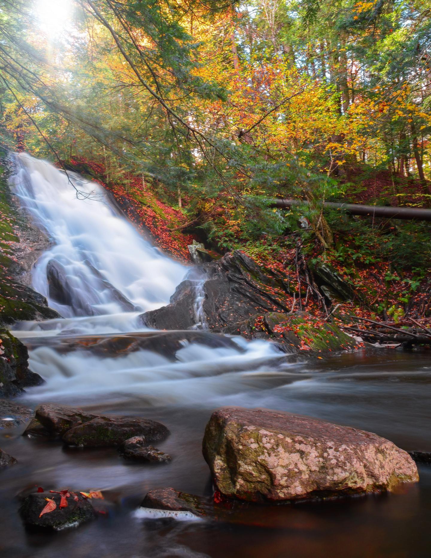 Waterfall surrounded by autumn trees and rocks.
