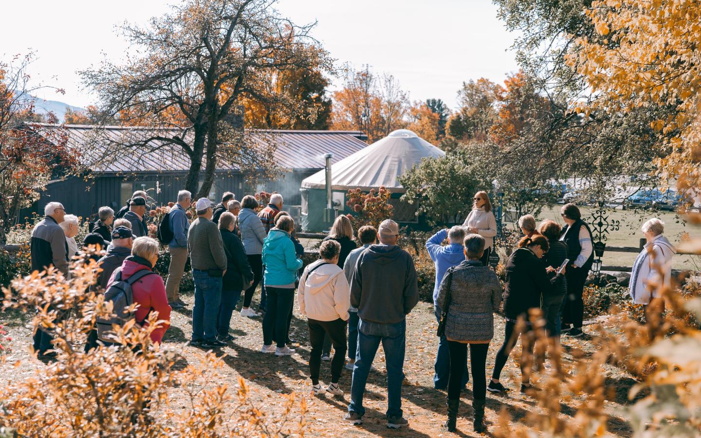 Group of people gathered outdoors in an autumn setting.