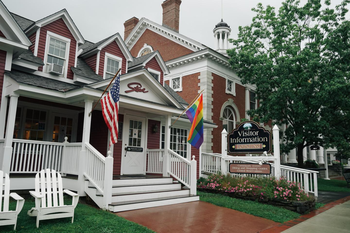 Red brick building with flags and a sign, overcast sky.