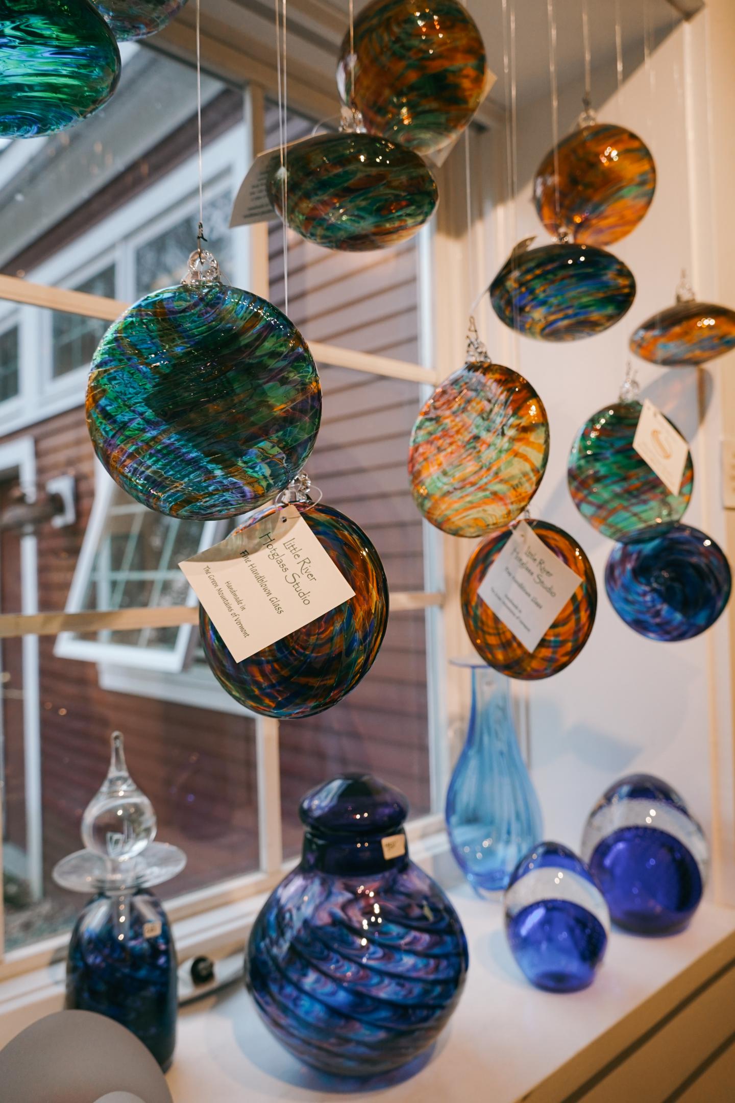 Colorful glass ornaments displayed in front of a window.