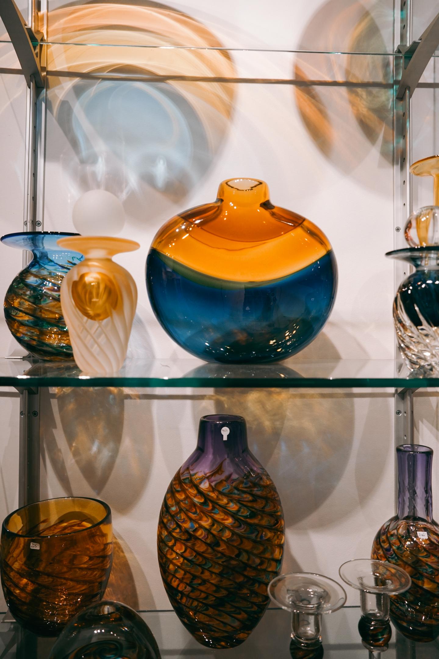 Colorful glass vases displayed on shelves.