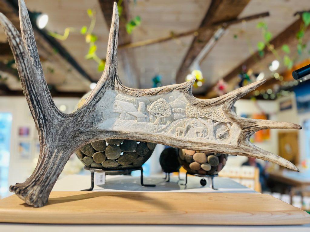 Carved antler with intricate designs in a rustic room setting.
