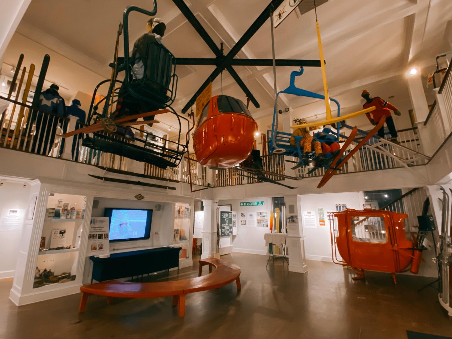 Museum interior with vintage cable cars suspended from the ceiling.
