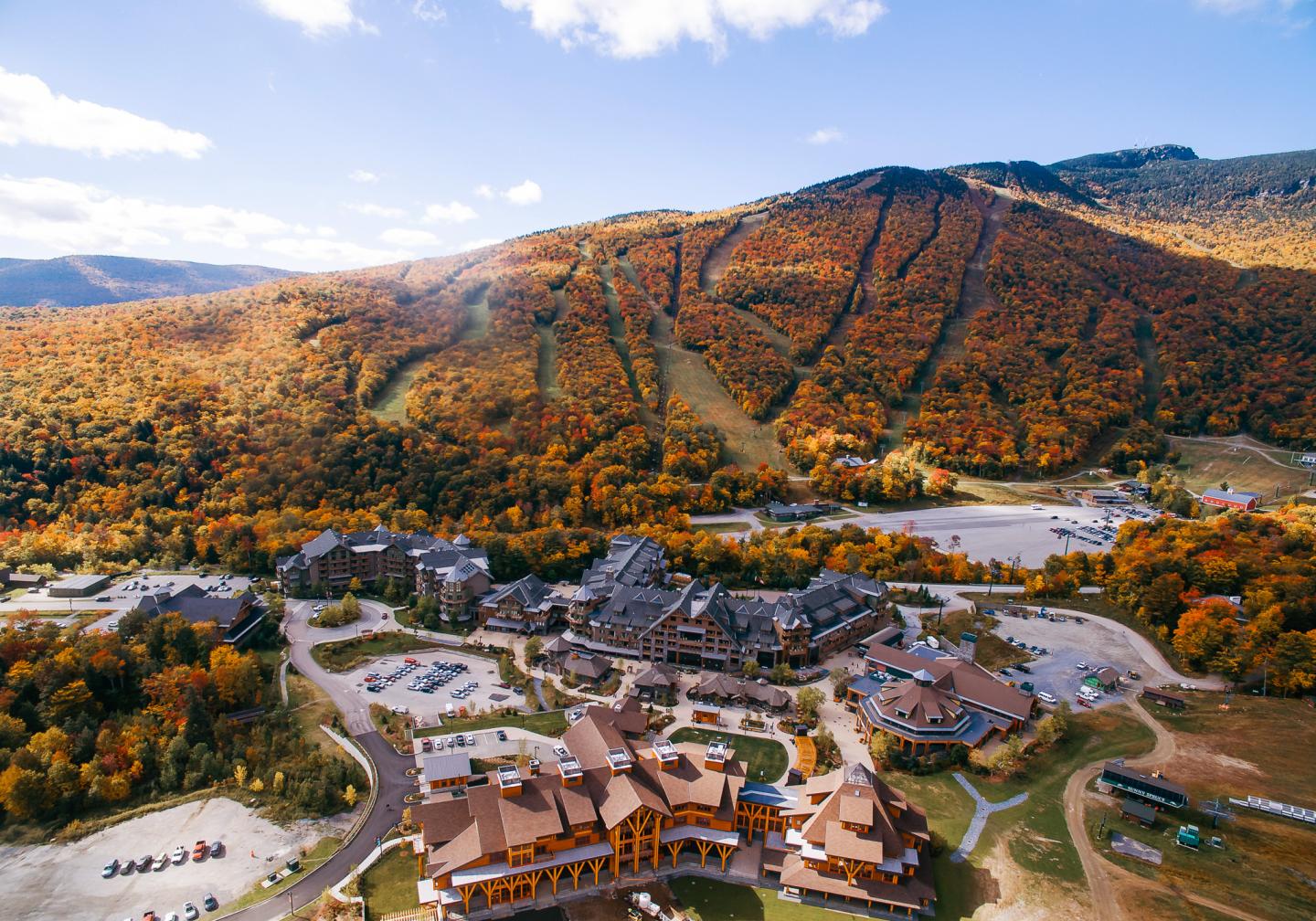 Aerial view of a resort nestled in colorful autumn mountains.