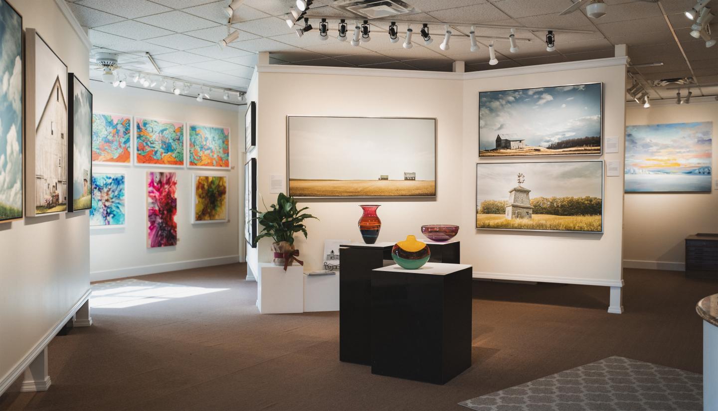 Art gallery interior with colorful paintings on walls and sculpture on a pedestal.