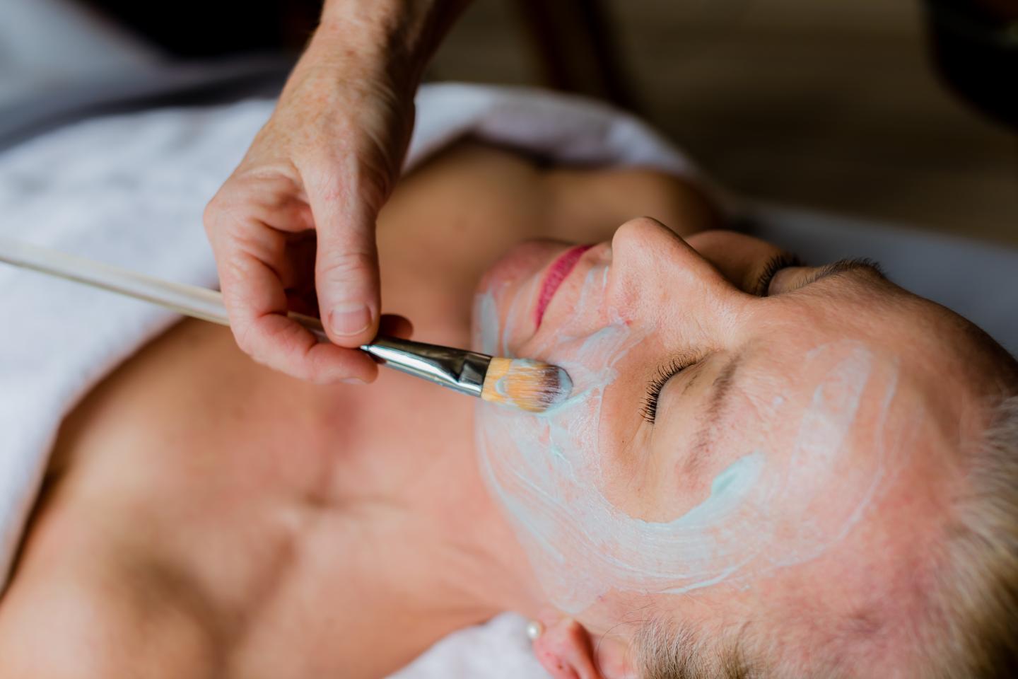 Woman receiving a facial treatment with a brush.