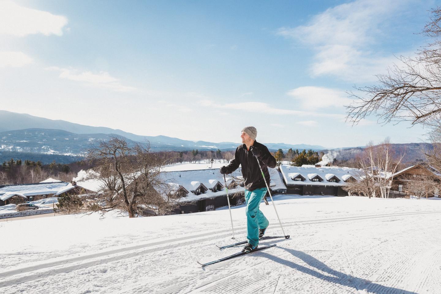 Skier gliding on snowy slope under clear blue sky.