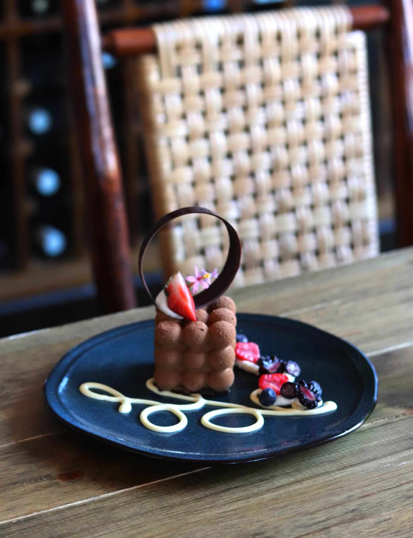 Chocolate dessert with berries on a black plate, elegant presentation.