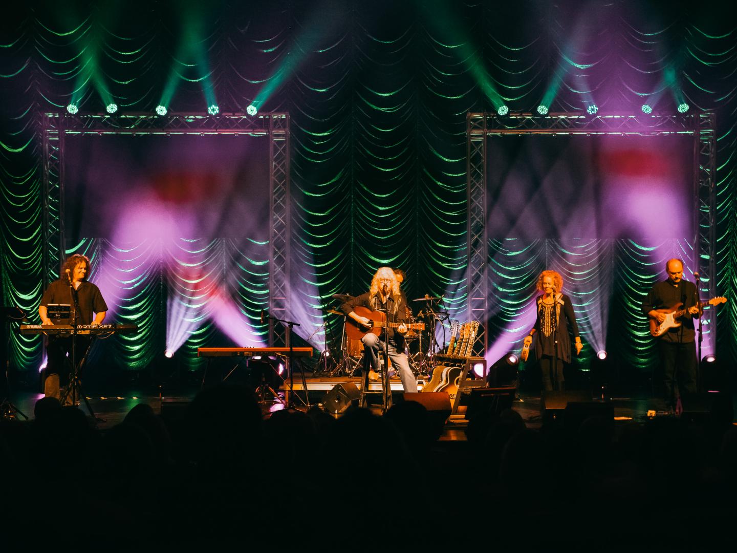 A band performs on stage with colorful lights and a dark backdrop.