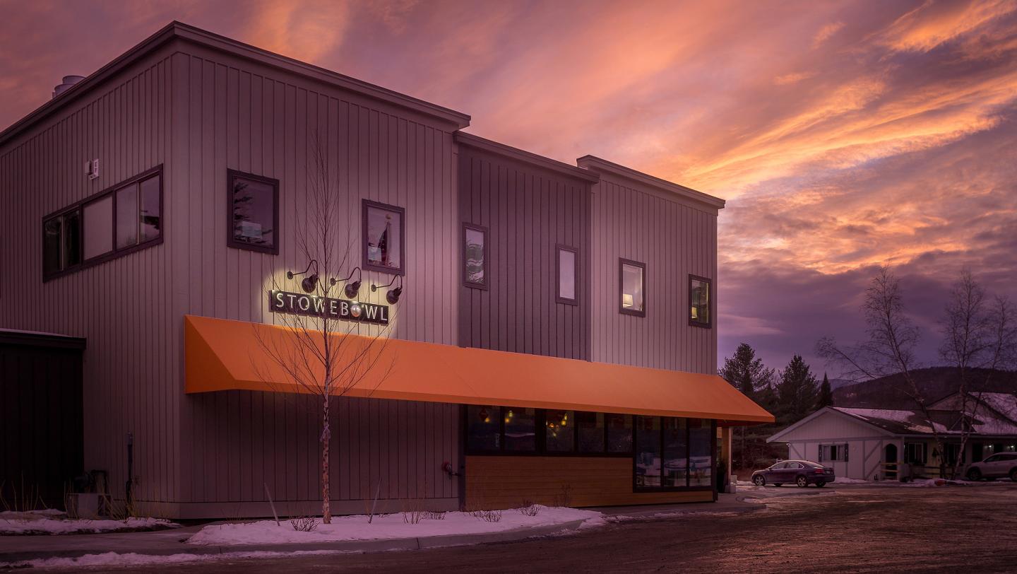 Modern building with orange awning at sunset, snow on the ground.