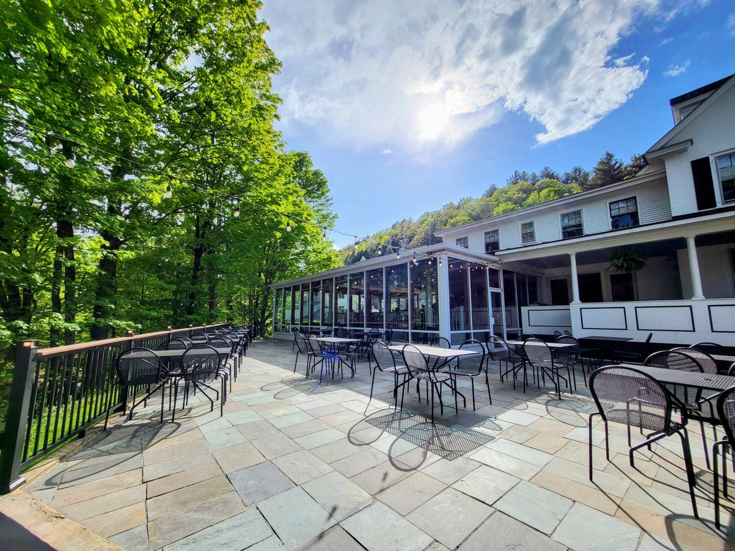 Sunny patio with empty tables, surrounded by trees and Grant's Restaurant.