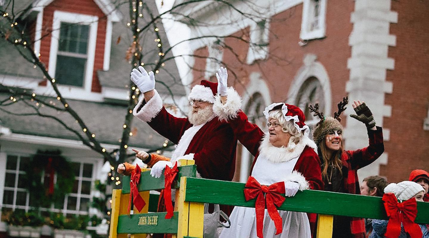 Santa and Mrs. Claus waving from a festive parade float.