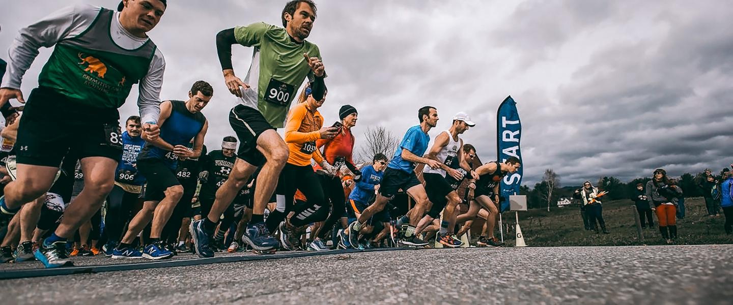Runners starting a race on a cloudy day, with a "Start" flag visible.