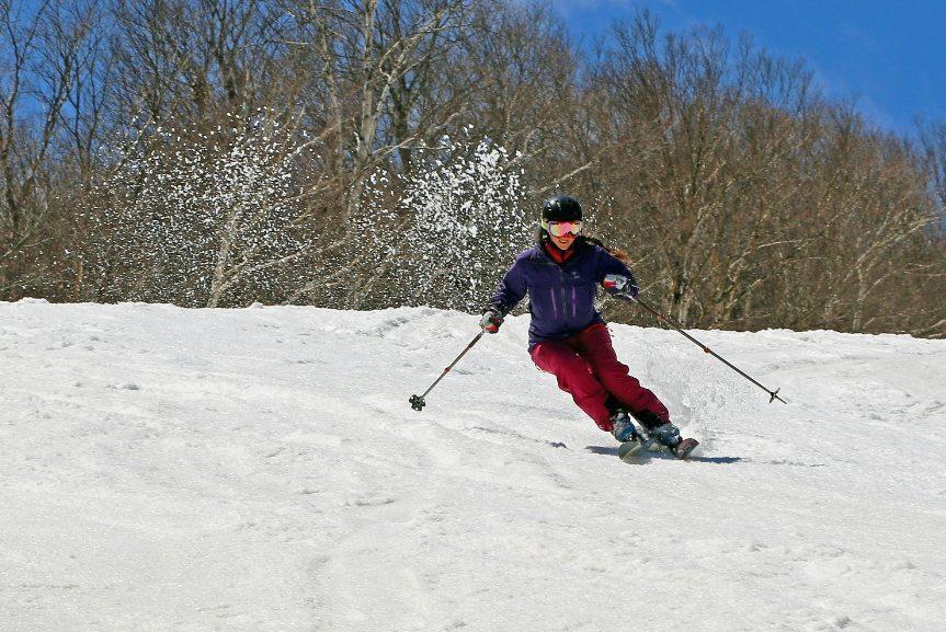 Skier in red pants skiing downhill on a snowy slope.