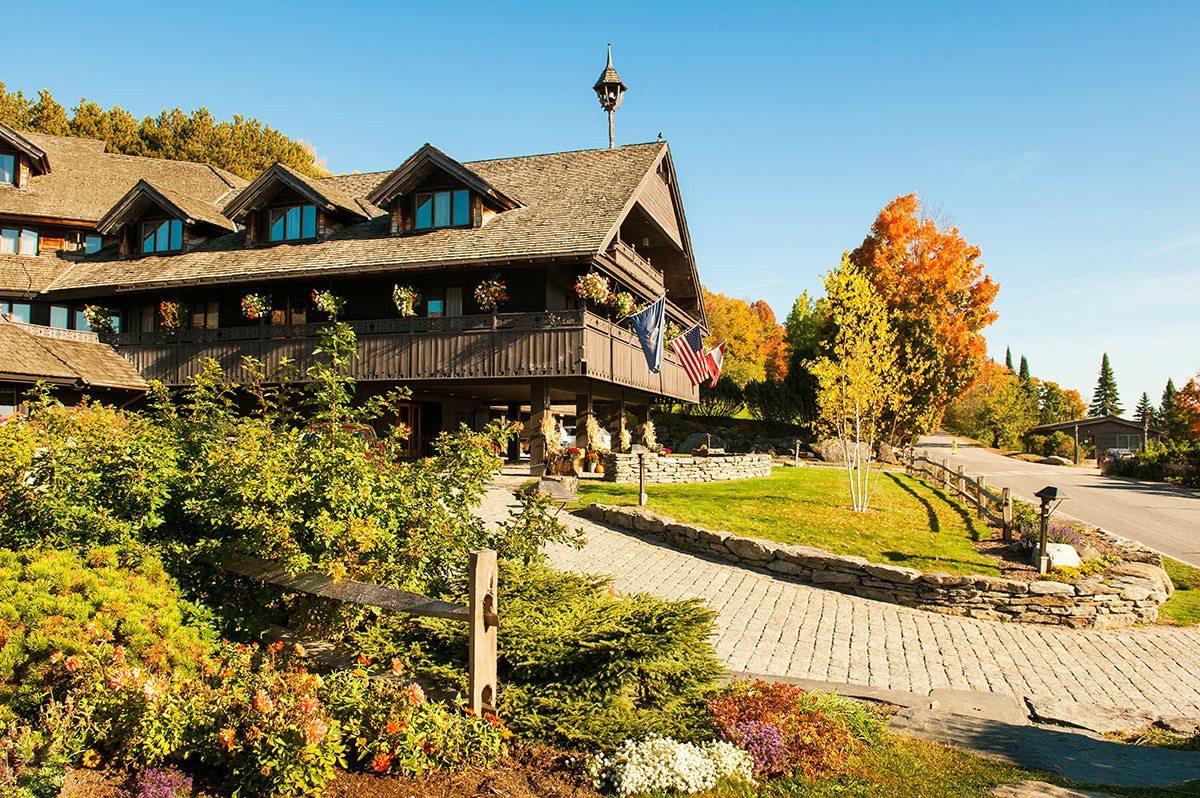 Rustic lodge with wooden exterior, surrounded by autumn trees under a clear blue sky.