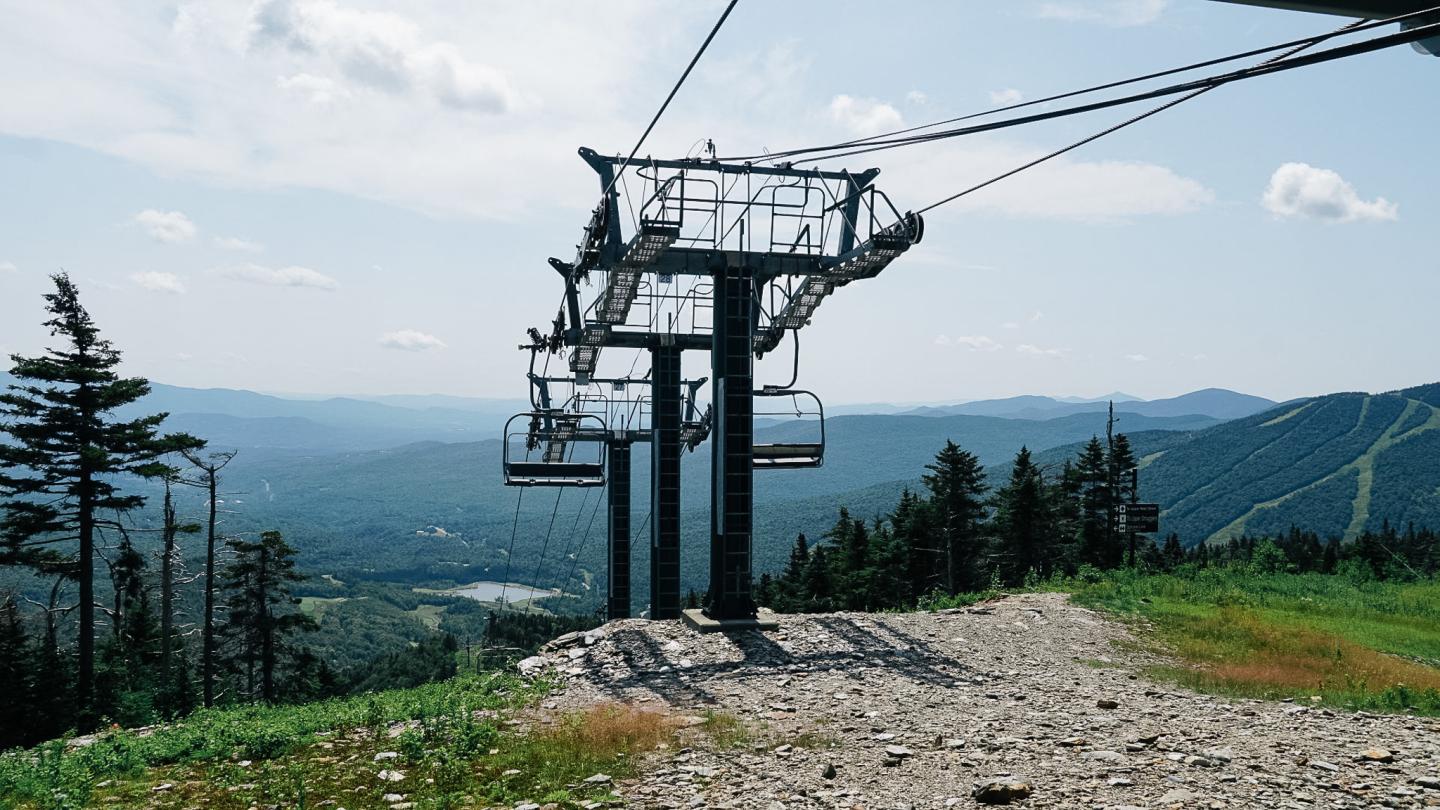Ski lift on a grassy mountain landscape under a clear sky.