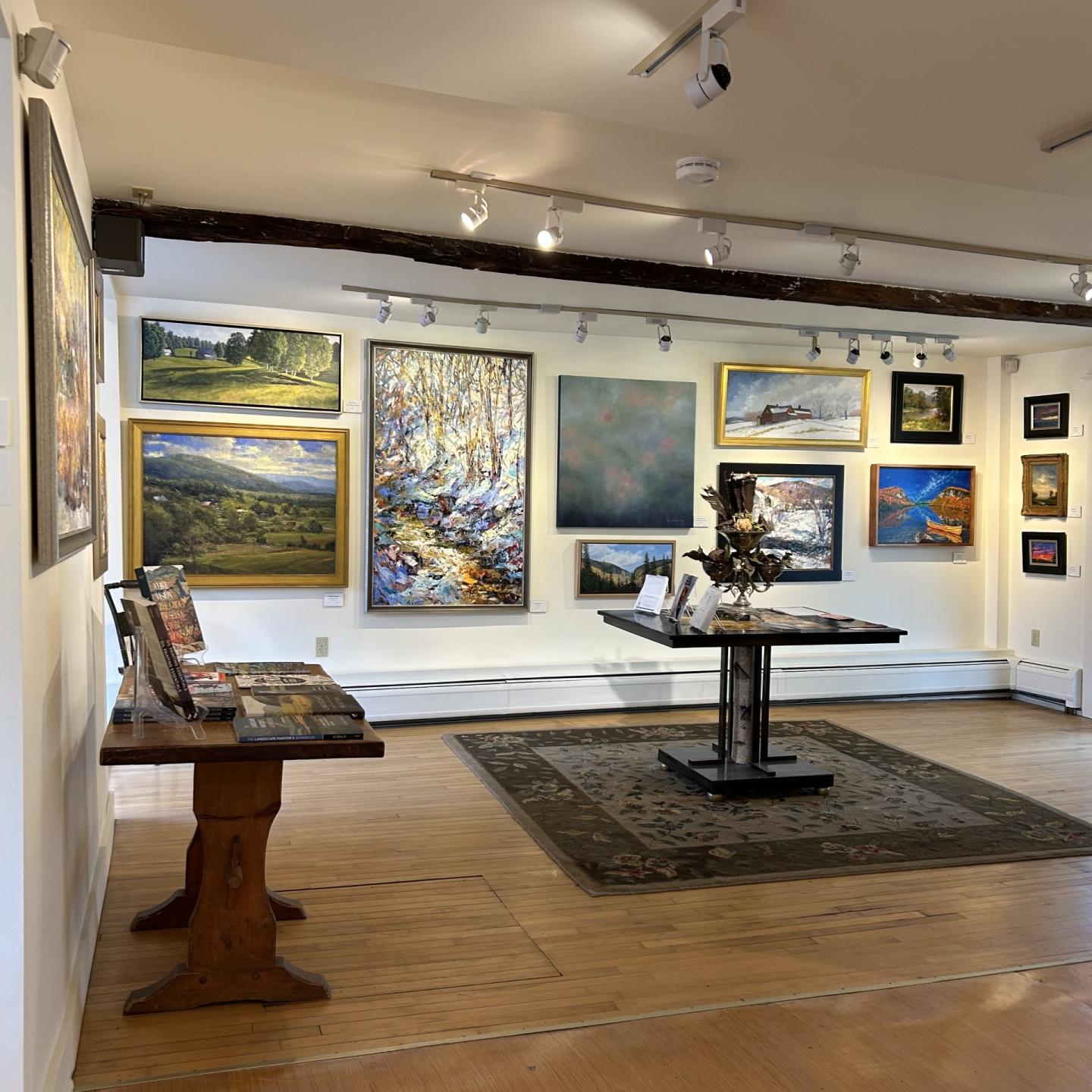 Art gallery with paintings on walls and a small central display table.