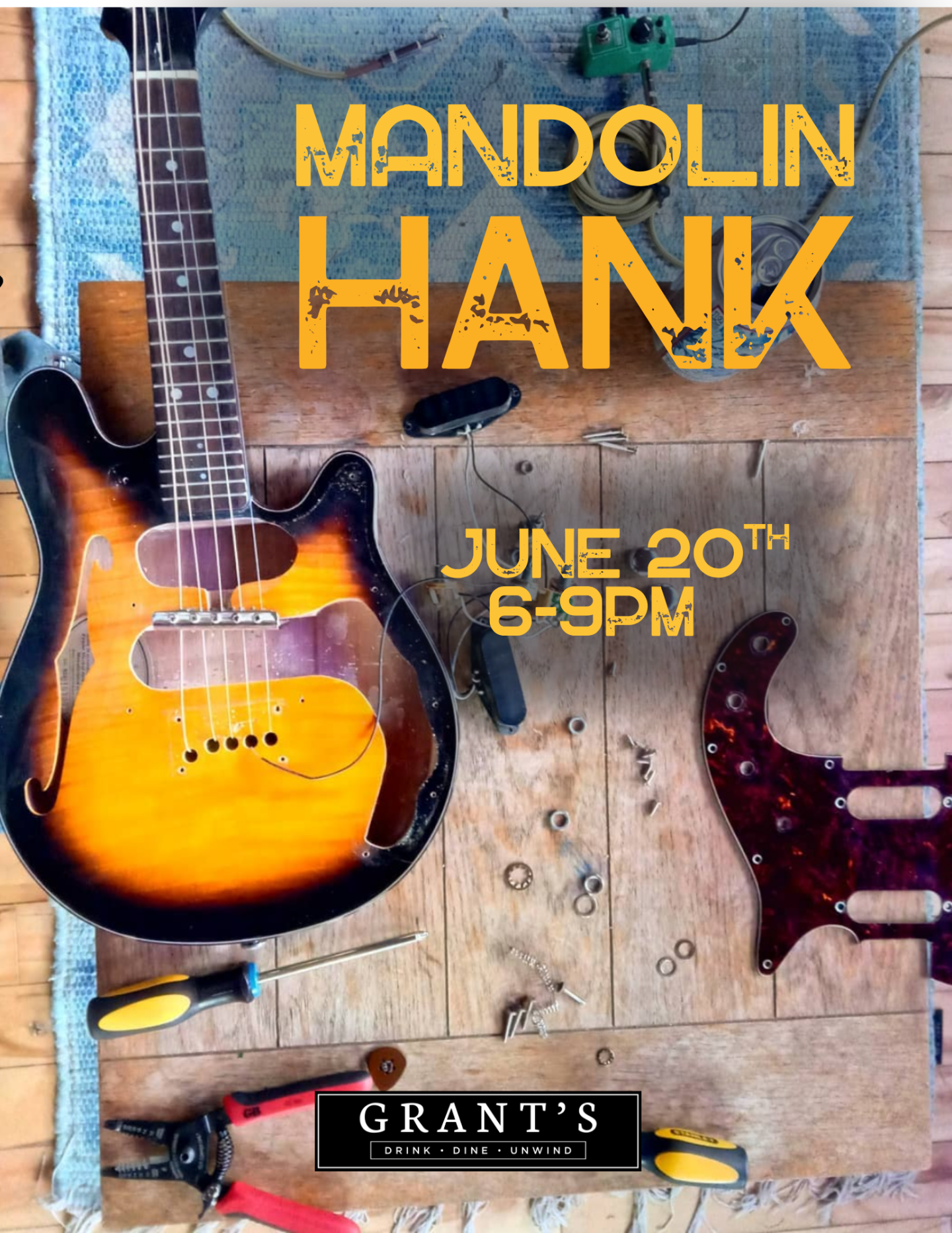 Sunburst electric mandolin on a workshop table with tools, Grant's music venue logo.