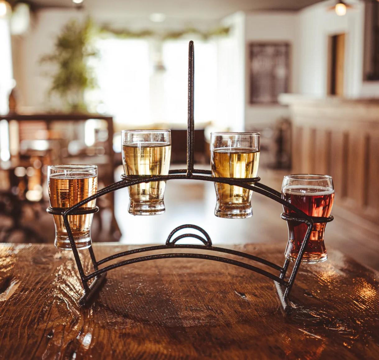 Beer flight on a wooden table in a cozy pub.