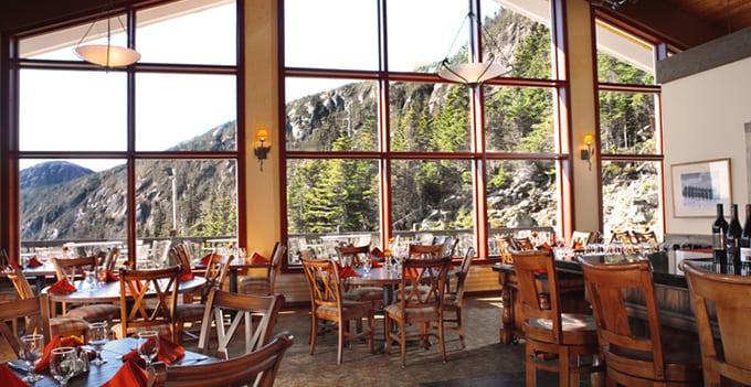 Dining area with wooden chairs, large windows, and a mountain view.