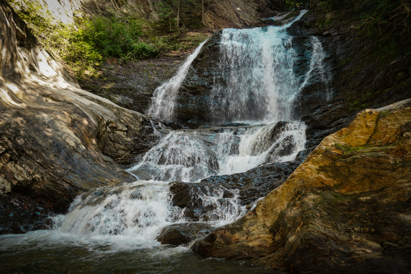 Waterfall cascading over multiple rock ledges in a forest setting.