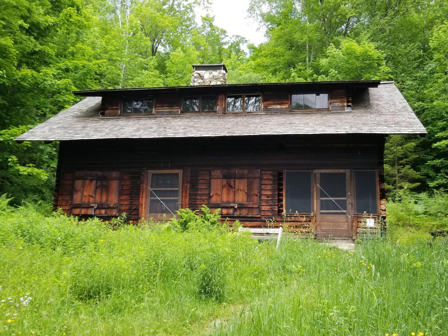Rustic wooden house surrounded by lush greenery and trees.