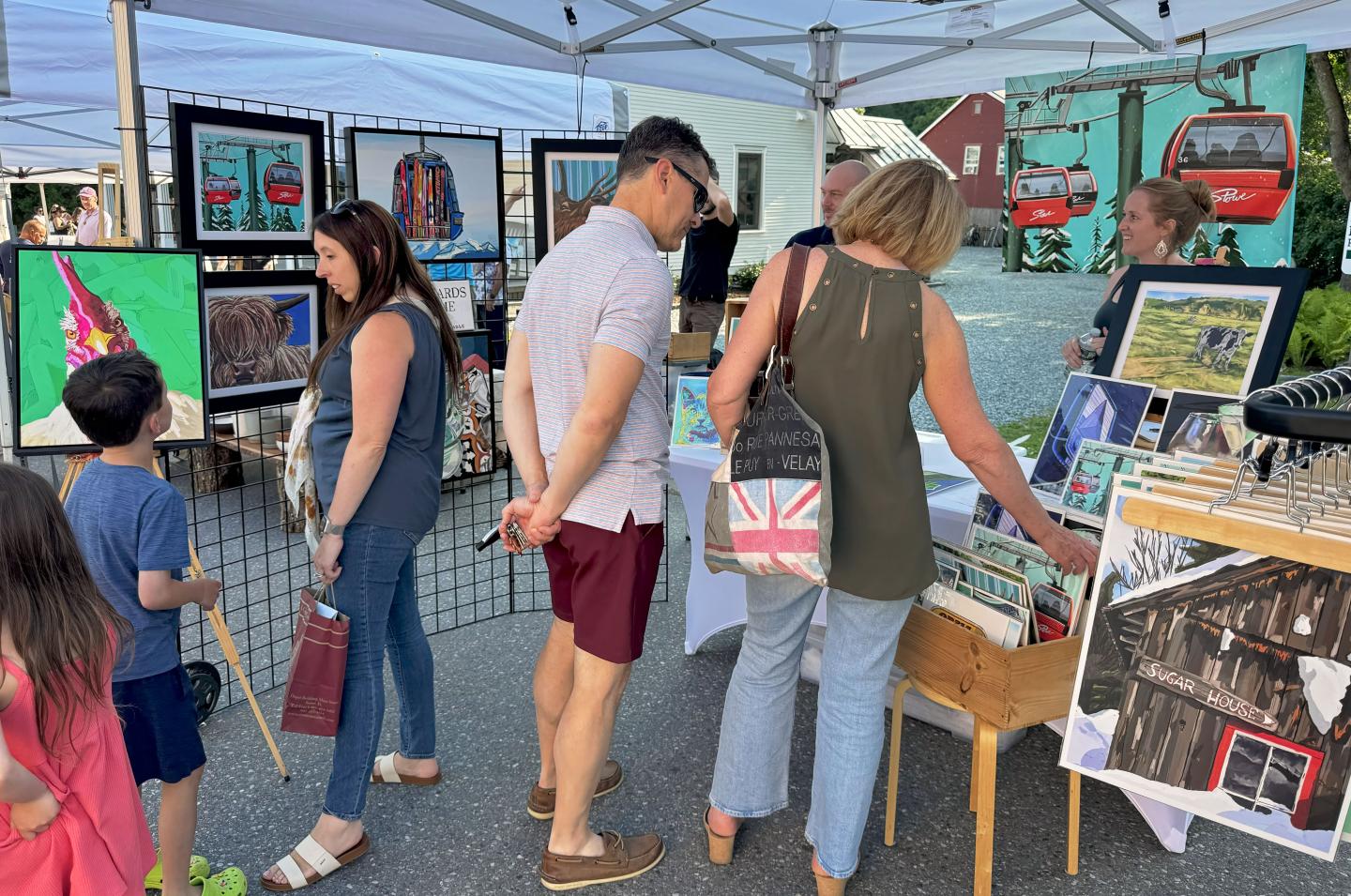Artisan market with people browsing paintings and prints.