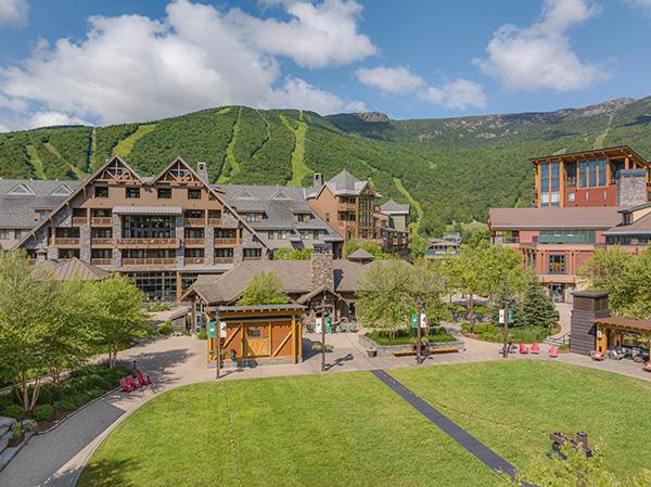 Resort buildings with mountain backdrop under blue sky.