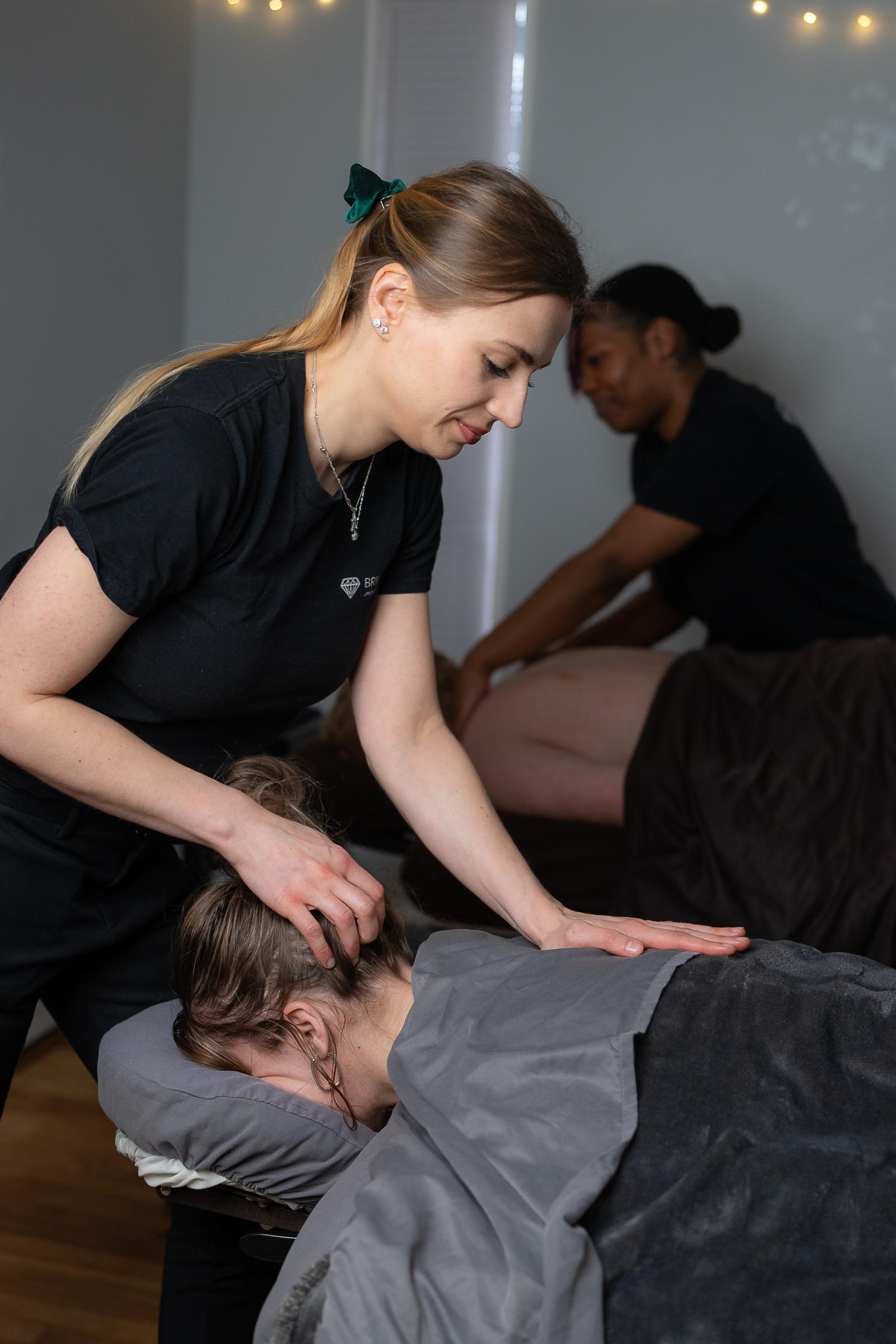 Two people giving massages in a calm, dimly lit spa setting.