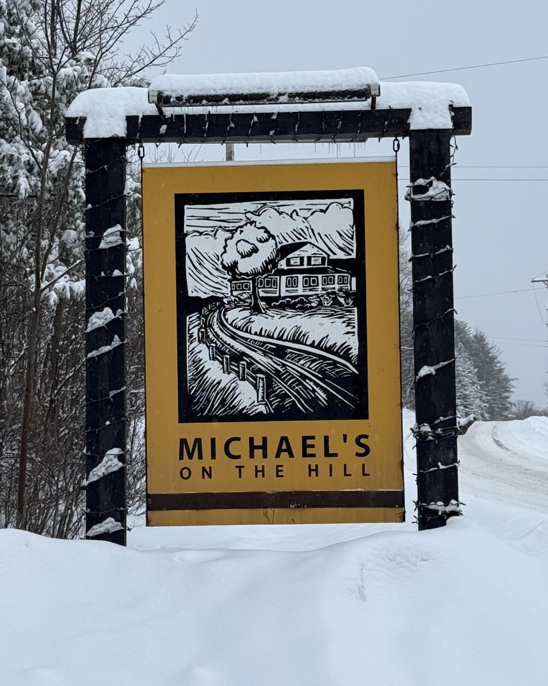 Sign for "Michael's on the Hill" in snowy landscape.