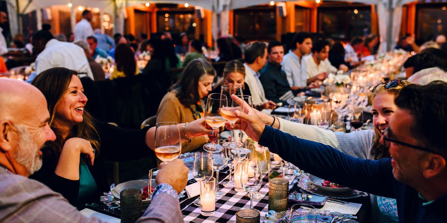 Attendees toast at a lively, candlelit banquet.