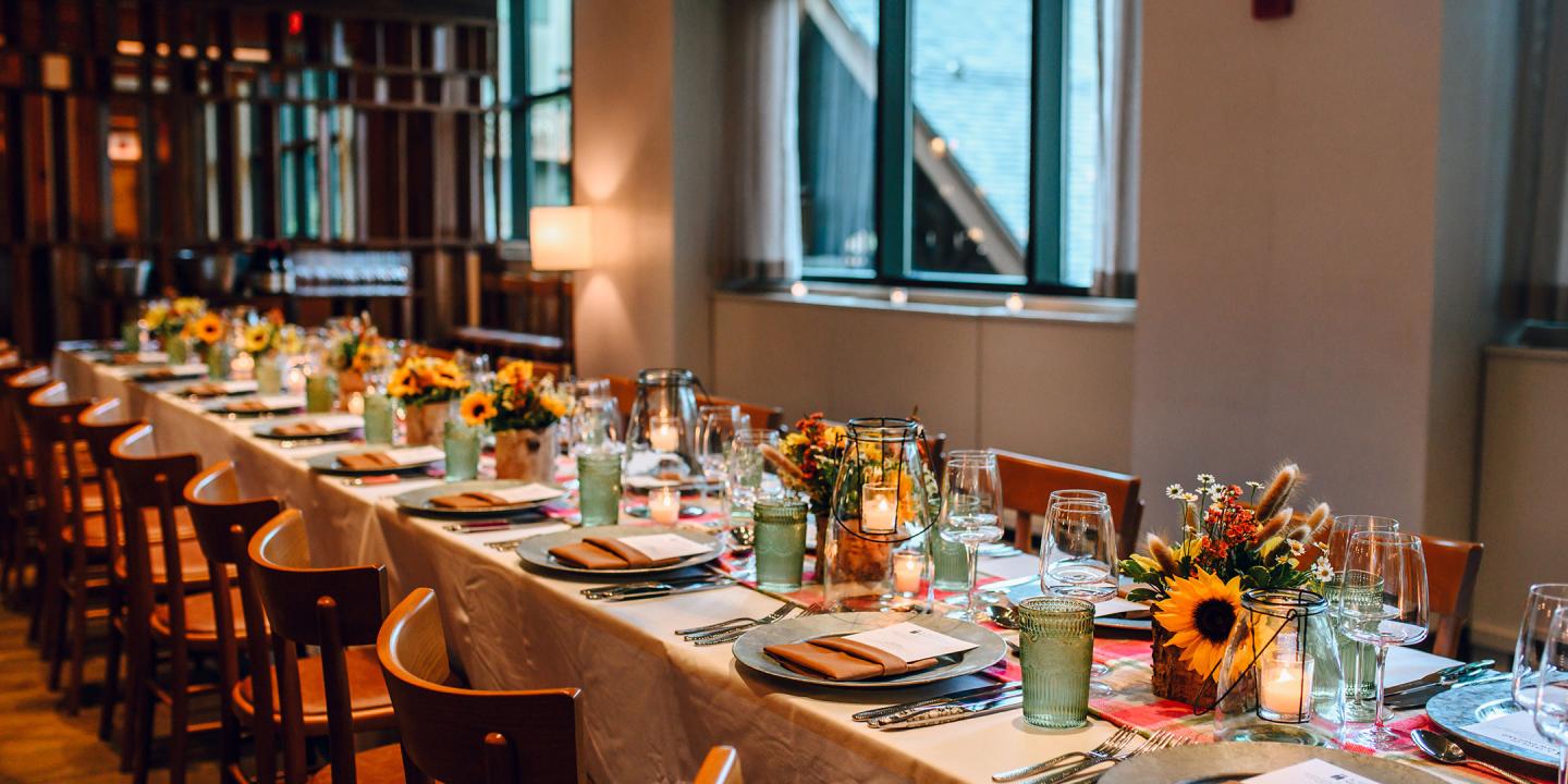 Elegant dining setup with long table, sunflower centerpieces, and candles.