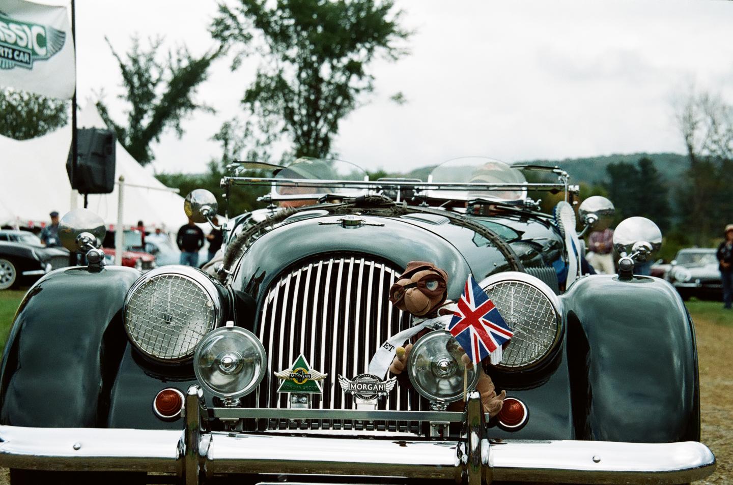 Close up of the hood of a vintage car front with a Union Jack flag, outdoors.