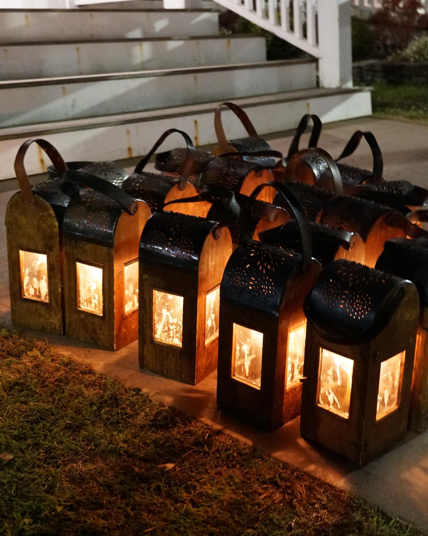 Lanterns glowing on pathway near steps at night.