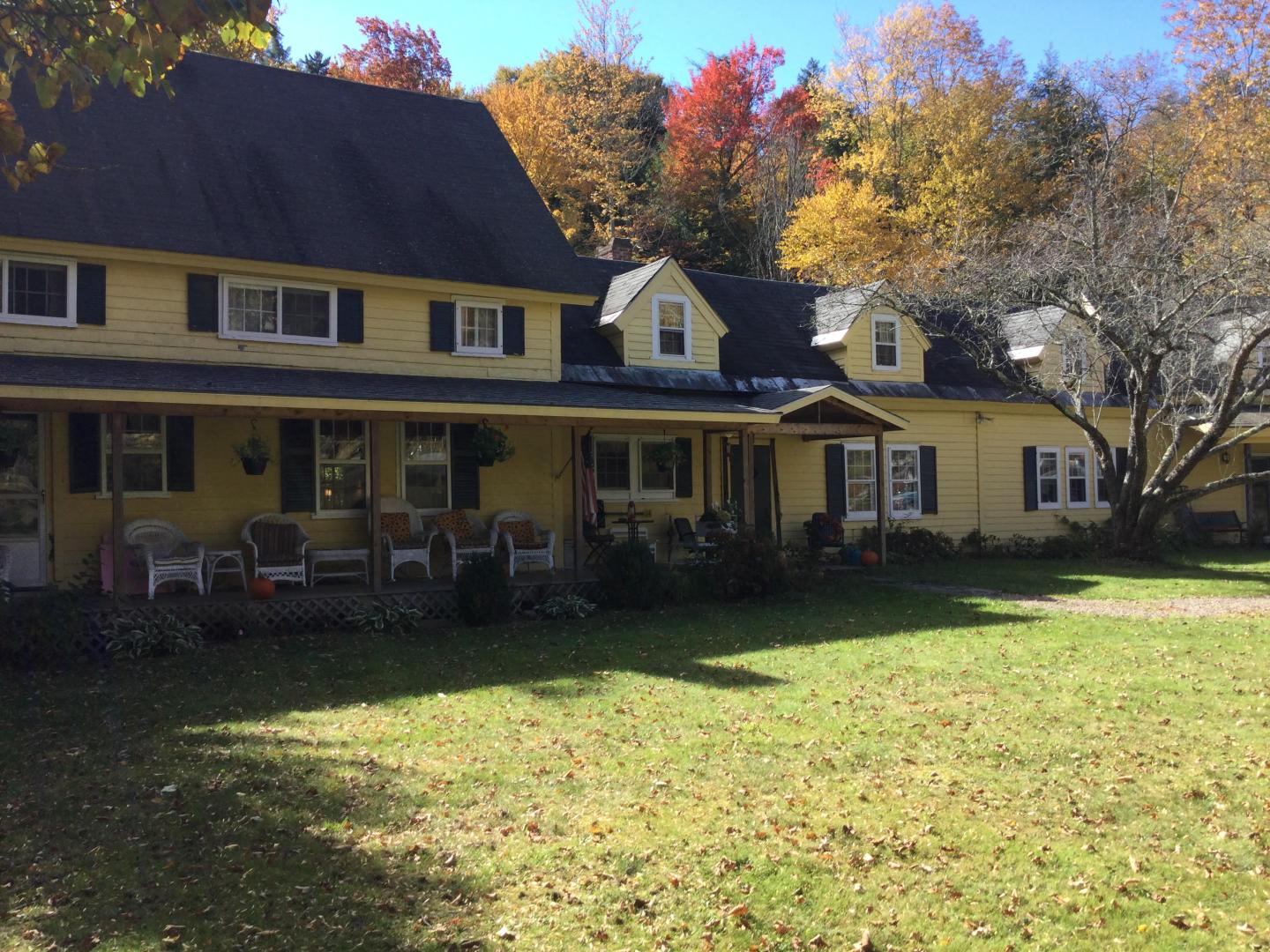 Yellow house with dark roof, surrounded by autumn trees.