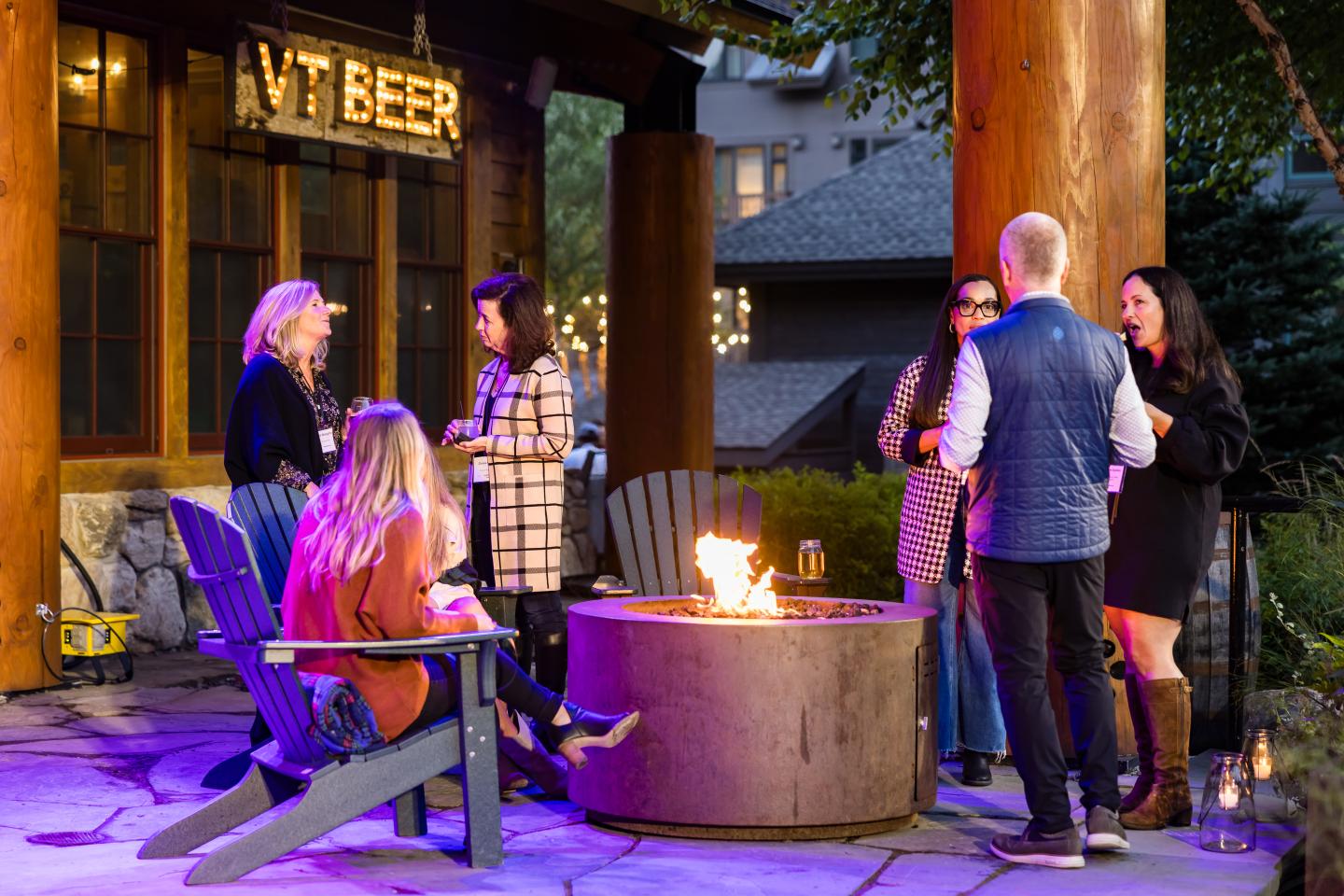 People gathered around a fire pit on a patio in the evening.
