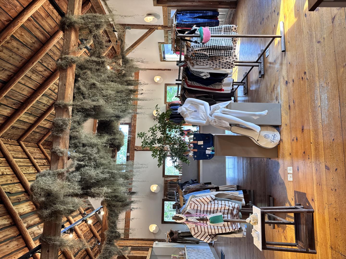Clothing boutique with wooden beams and hanging greenery.