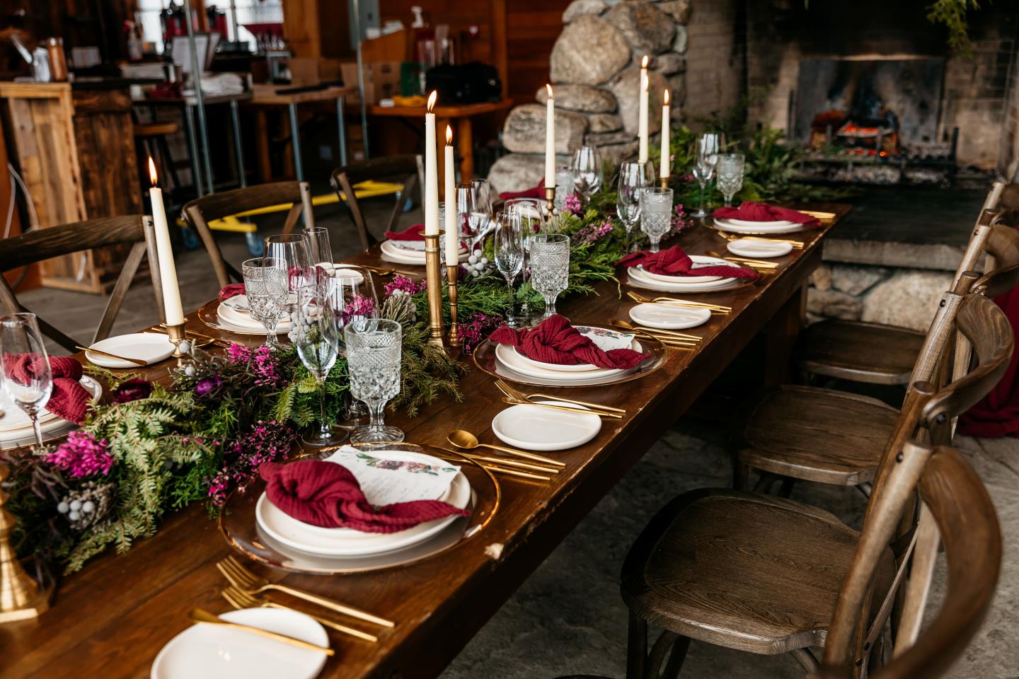 Elegant dining table set with red napkins, candles, and floral centerpiece.