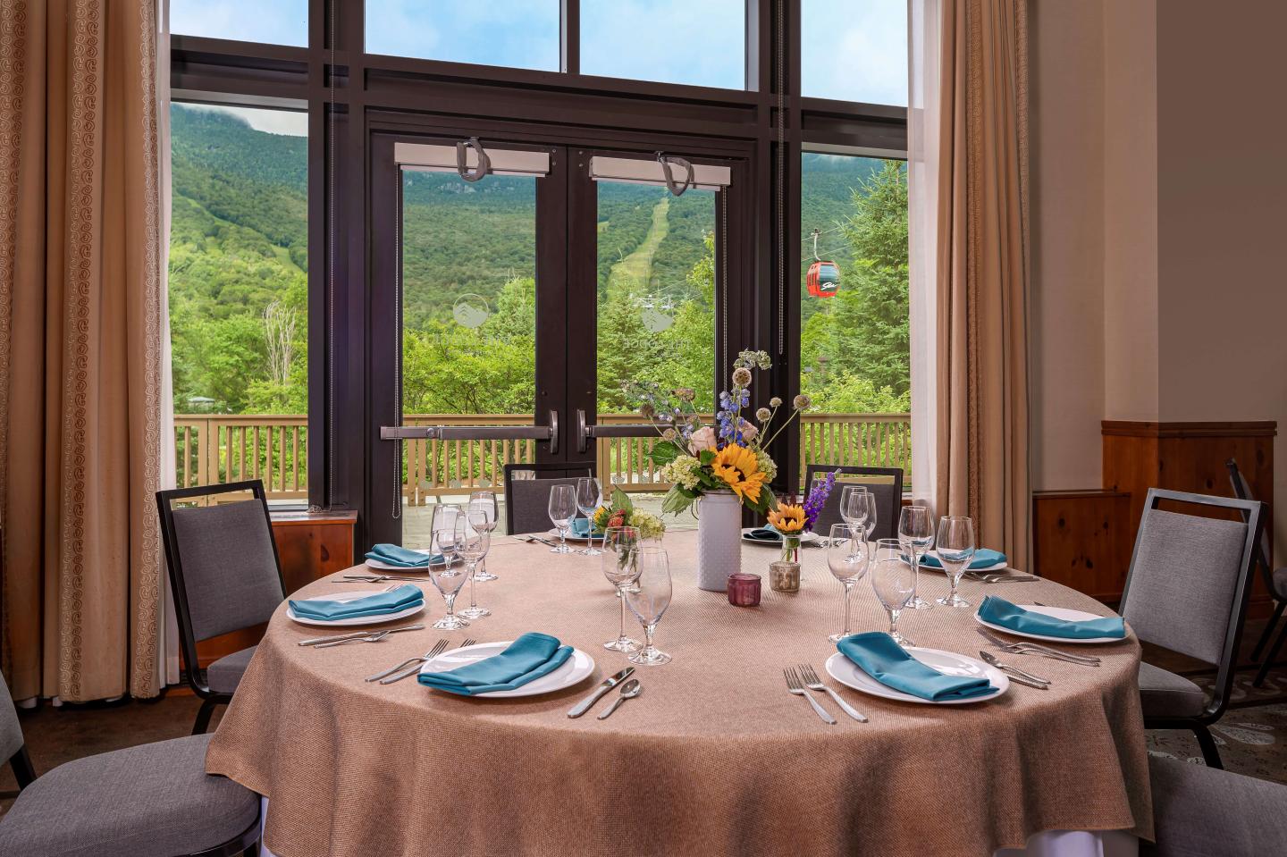 Elegant dining table set for six, with mountain view through large windows.