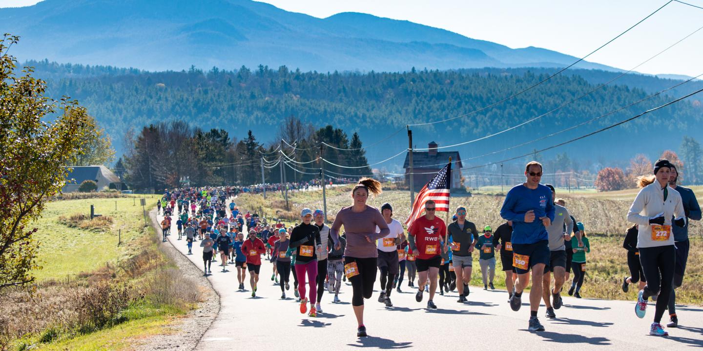 Runners in a race on a rural road, mountains in the background.