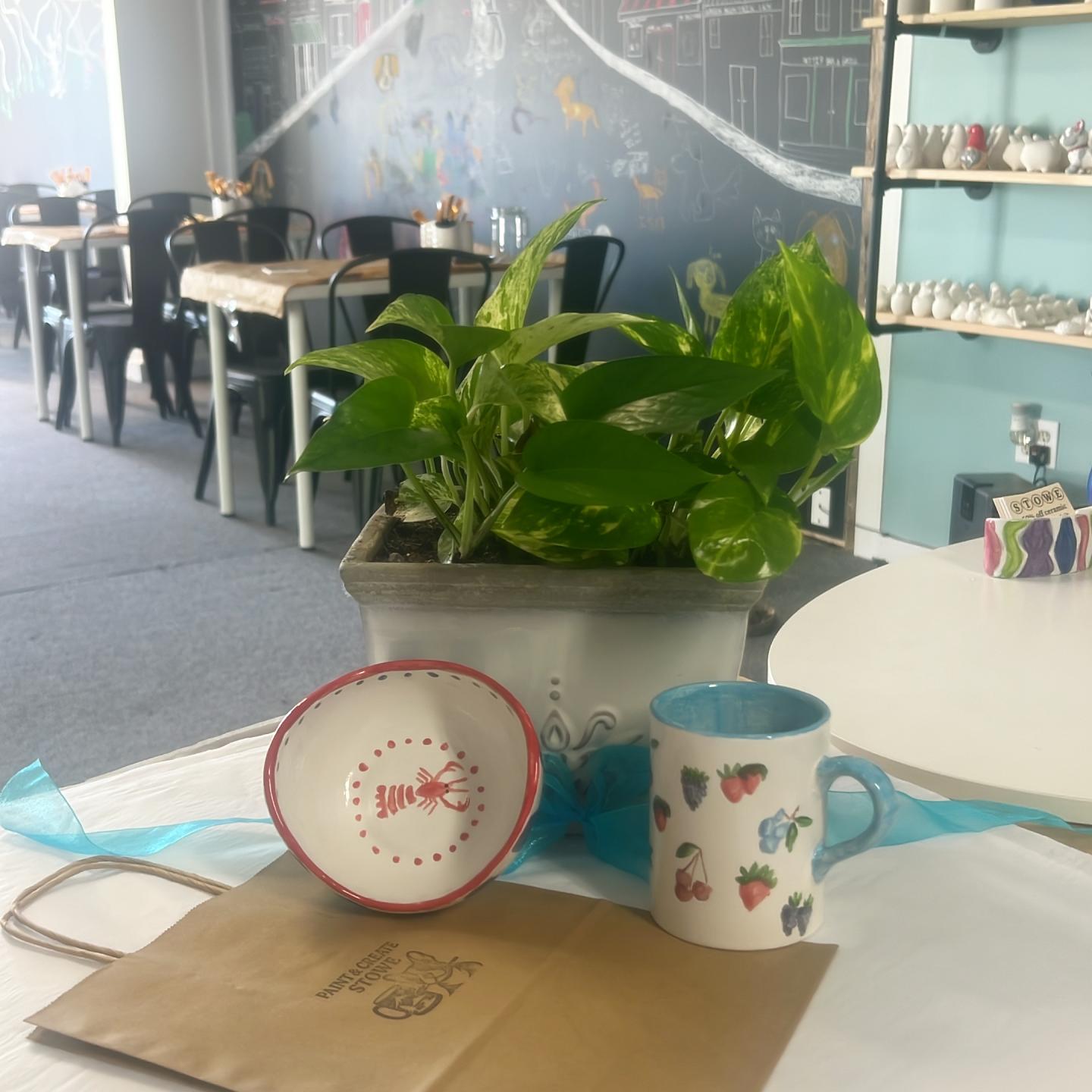 Potted plant with mugs on table in a cafe setting.