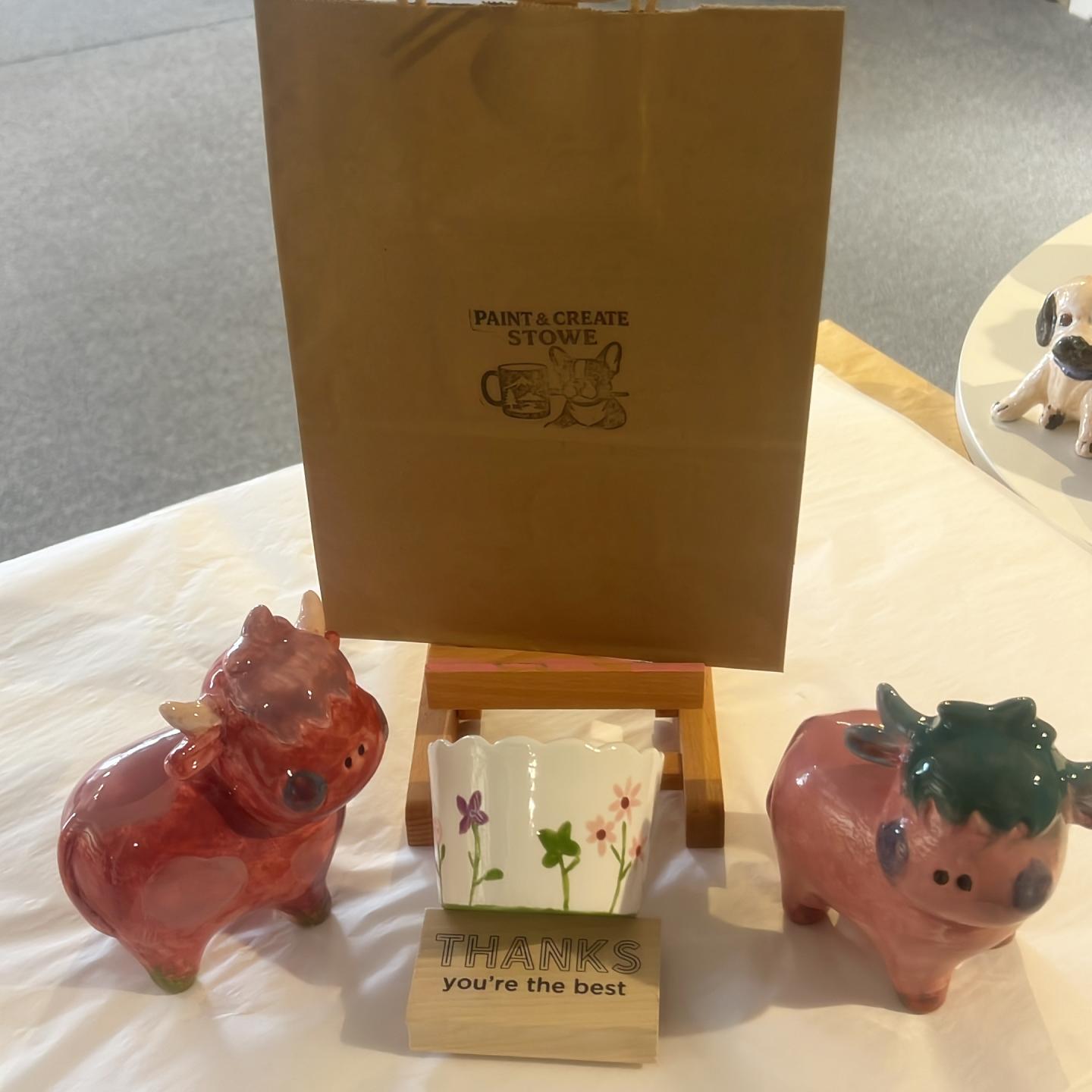 Ceramic cows, gift bag, and cup on a table display.