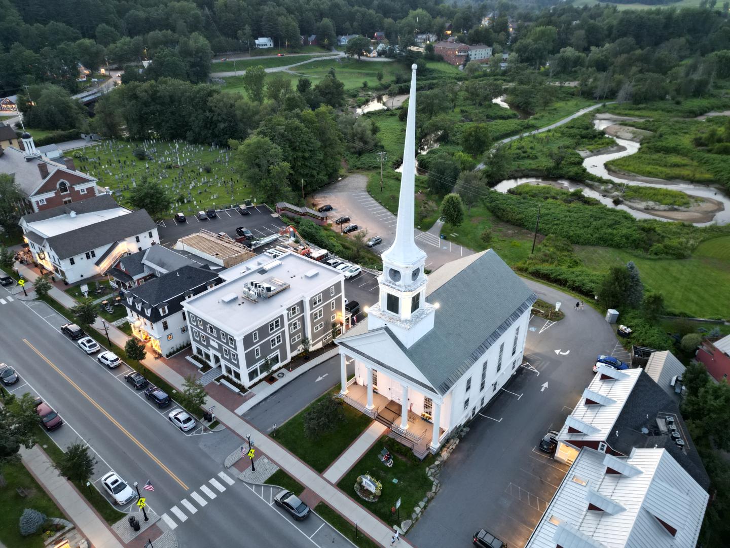 Aerial view of a small town with a prominent white church and green landscape.