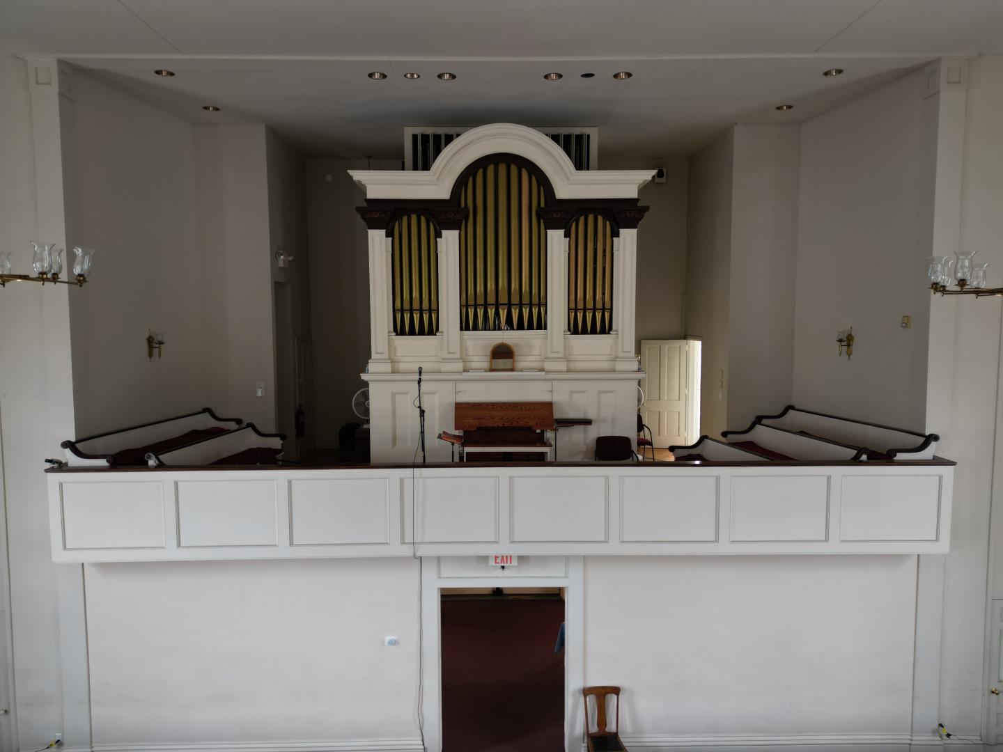 An empty church balcony with an organ and benches.