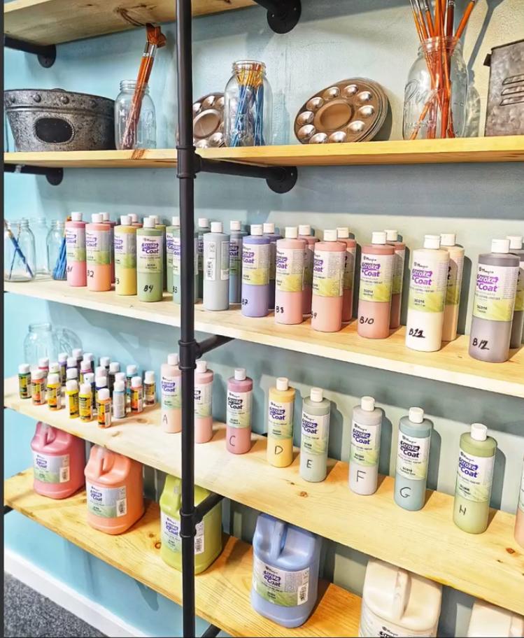 Shelves with colorful paint bottles and art supplies in a store display.