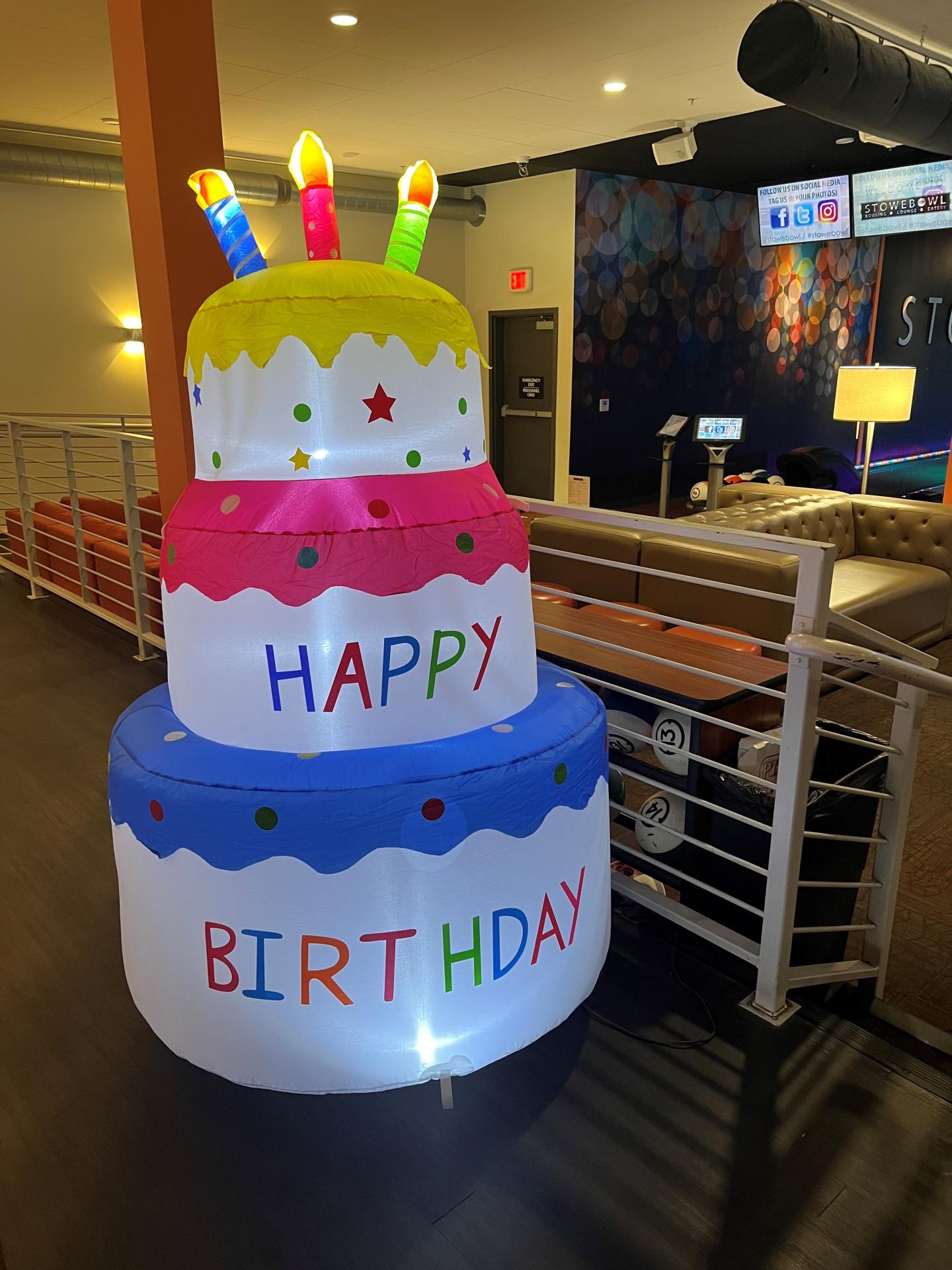 Inflatable birthday cake with colorful candles and "Happy Birthday" text.