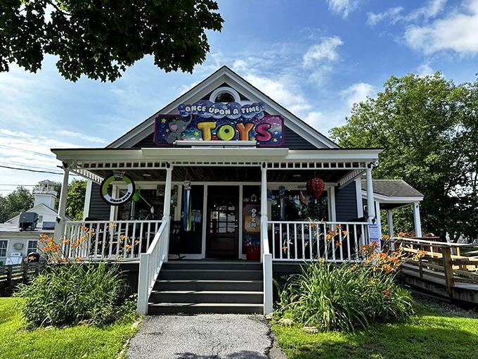 Toy store with a colorful sign, white porch, and blooming flowers.