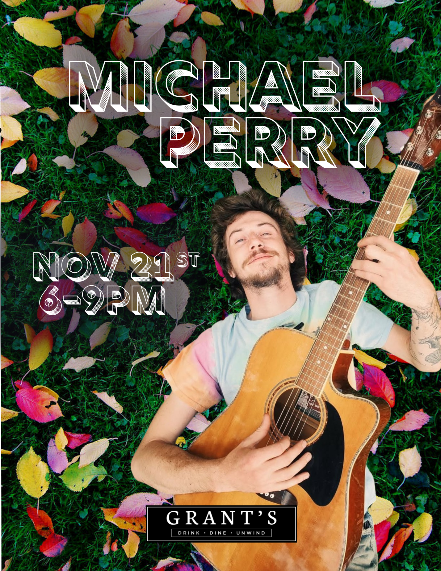 Man smiling while playing guitar, surrounded by colorful leaves.