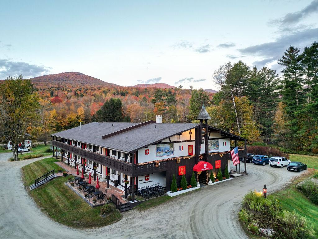 Lodge surrounded by colorful autumn trees and mountains in the background.